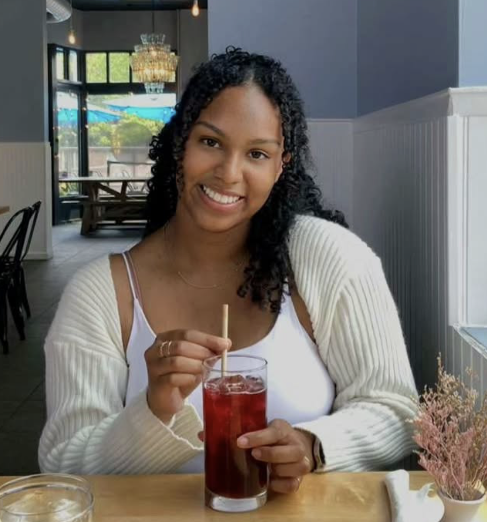 Student smiling at camera holding a drink and straw