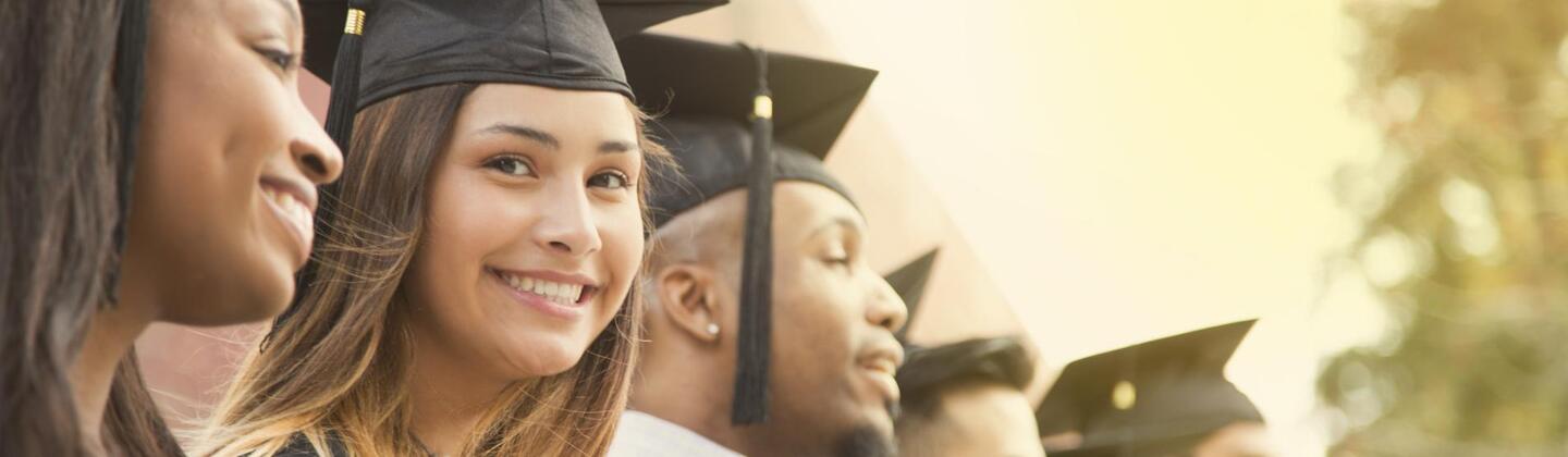 Group of graduated students with one smiling directly at the camera