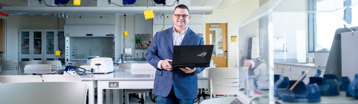 Miguel Martinez in a lab holding laptop