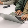 Student typing on a laptop on a desk in a classroom