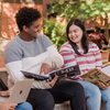 Photo of students sitting outside at UMBC talking, smiling, and looking at UMBC booklets